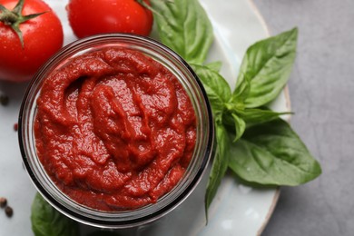 Jar of tasty tomato paste and ingredients on table, flat lay