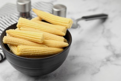 Photo of Bowl of pickled baby corn on white marble table, closeup. Space for text