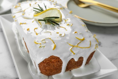 Photo of Tasty lemon cake with glaze and rosemary on white marble table, closeup