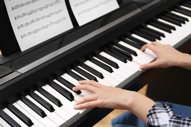 Young woman playing piano at home, closeup