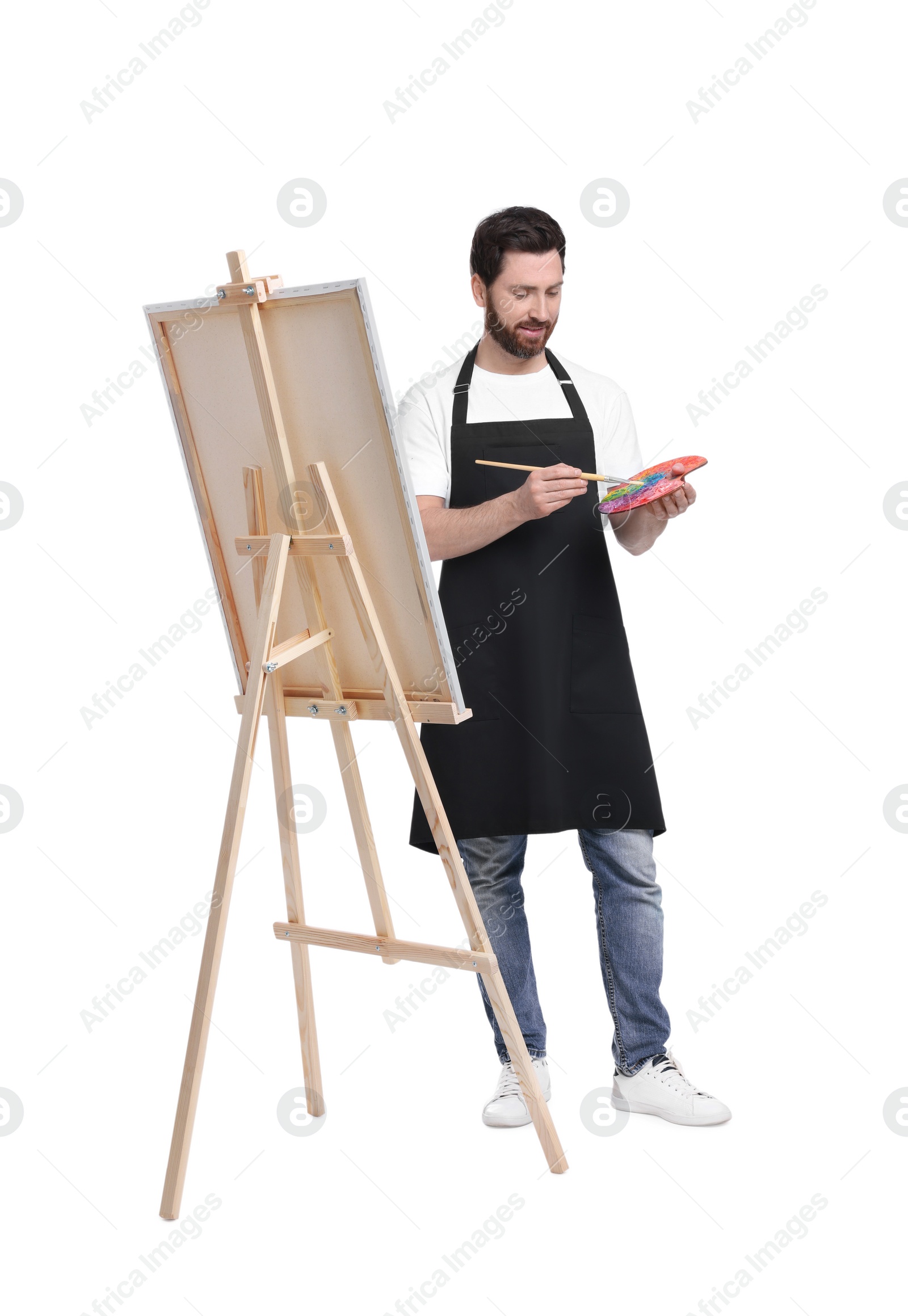 Photo of Artist with brush painting against white background. Using easel to hold canvas