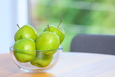 Photo of Bowl of fresh green apples on table indoors. Space for text