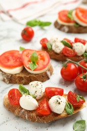 Photo of Delicious sandwiches with mozzarella, fresh tomatoes and basil on white marble table