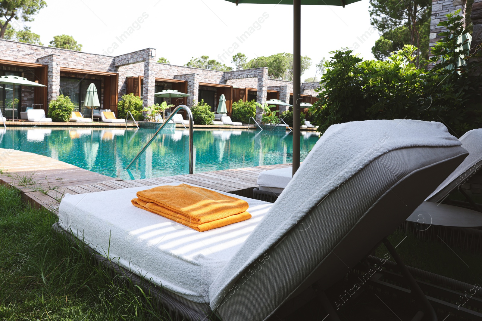 Photo of Sunbeds near outdoor swimming pool at luxury resort