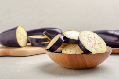 Photo of Wooden bowl with cut eggplant on table