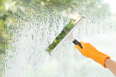 Janitor cleaning window with squeegee indoors, closeup