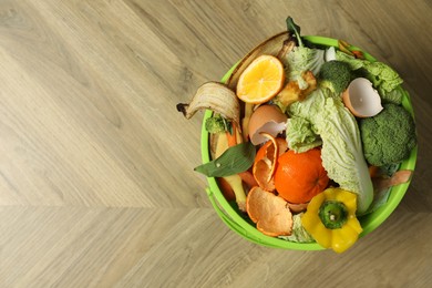 Photo of Natural garbage in trash bin on wooden background, top view with space for text. Composting of organic waste