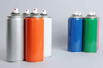 Photo of Colorful cans of spray paints on light grey background