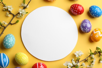 Photo of Flat lay composition with painted Easter eggs and blank card on color background, space for text