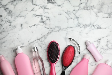 Photo of Flat lay composition with hair cosmetic products and tools on marble background. Space for text