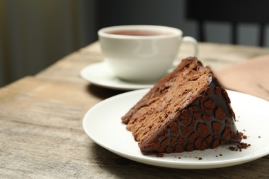 Piece of delicious chocolate truffle cake on wooden table, closeup. Space for text