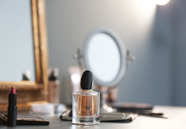 Bottle of perfume and makeup products on dressing table