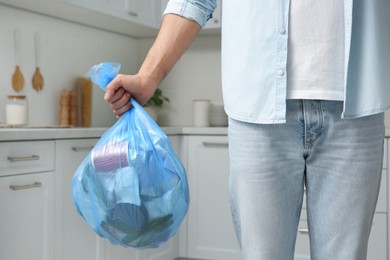 Man holding full garbage bag at home, closeup