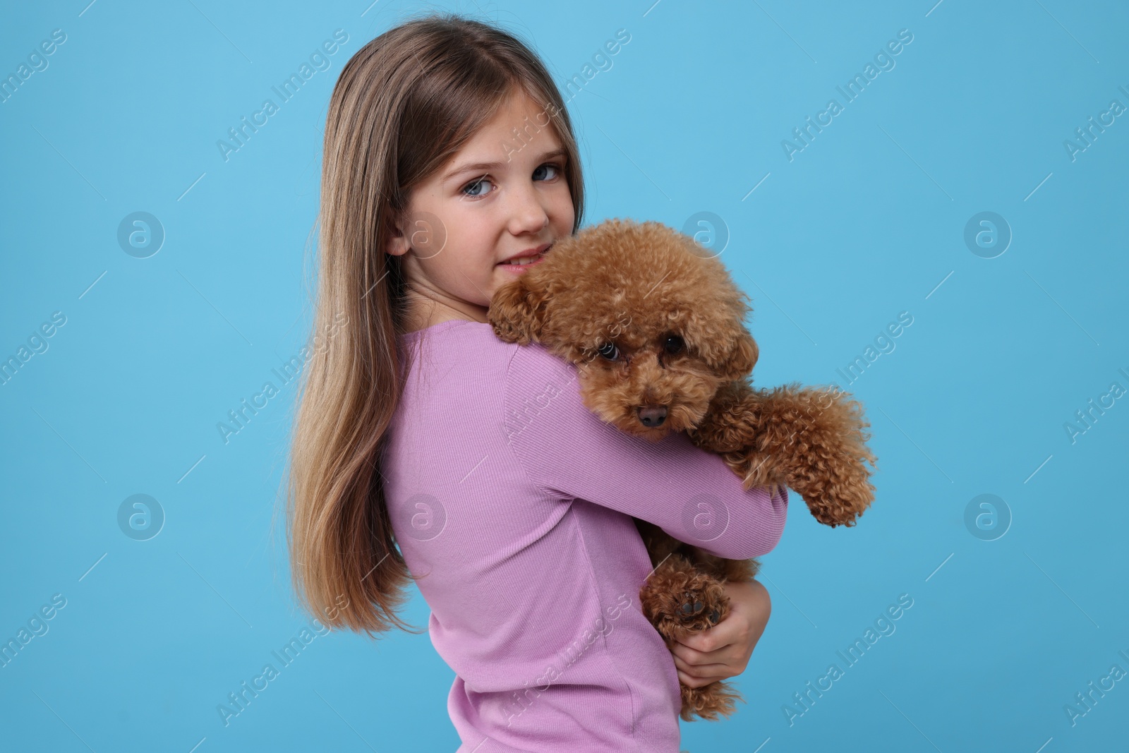 Photo of Little child with cute puppy on light blue background. Lovely pet