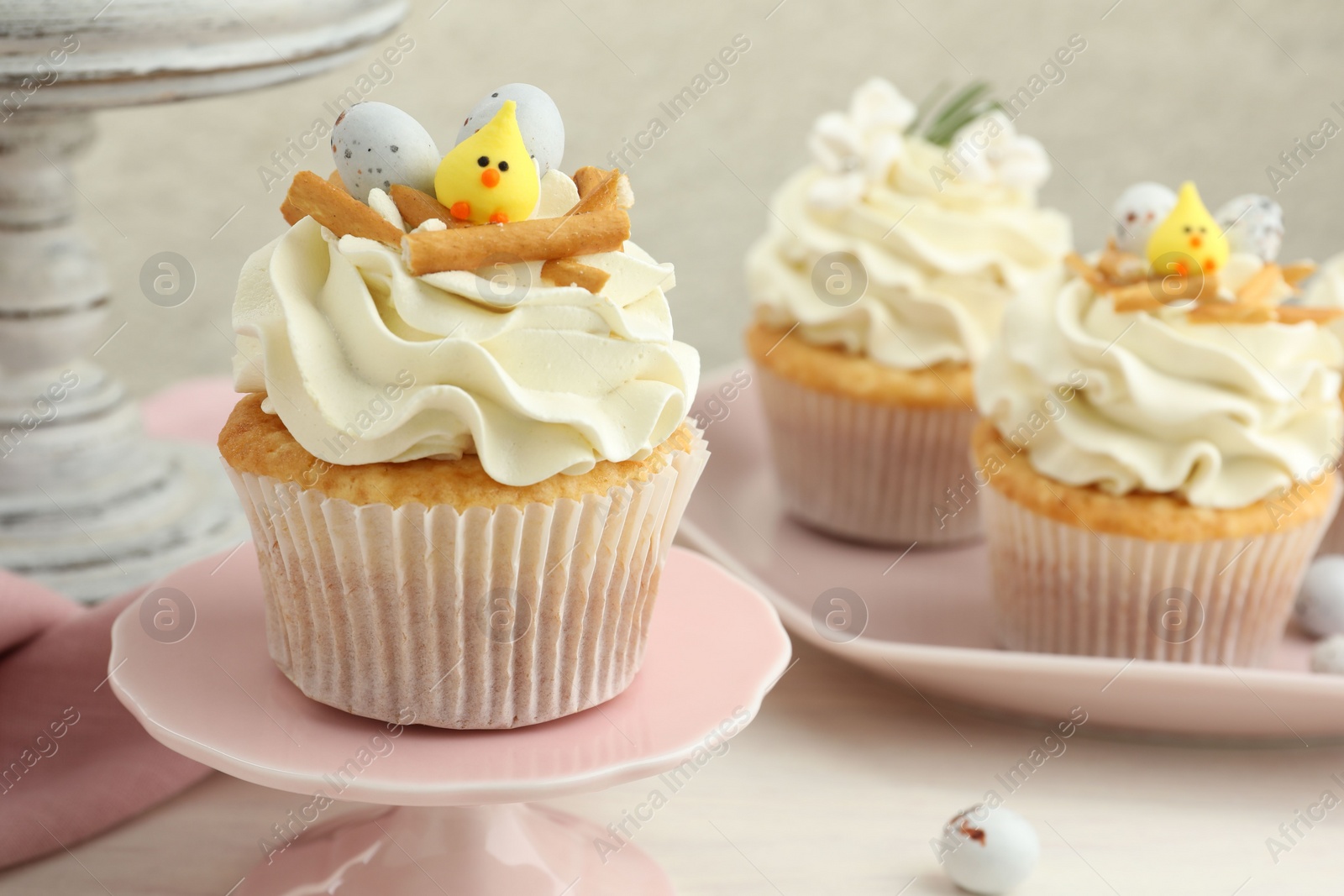 Photo of Tasty Easter cupcakes with vanilla cream on light table