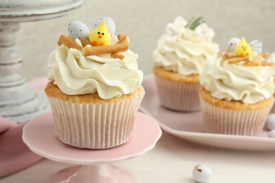 Tasty Easter cupcakes with vanilla cream on light table