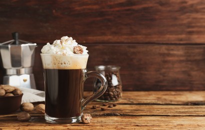 Photo of Coffee drink with nutmegs and whipped cream on wooden table. Space for text