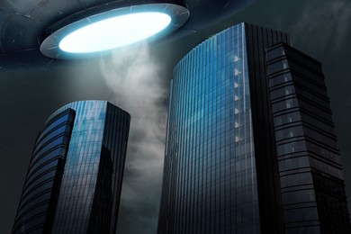 Image of Alien spaceship emitting light over buildings. UFO, extraterrestrial visitors