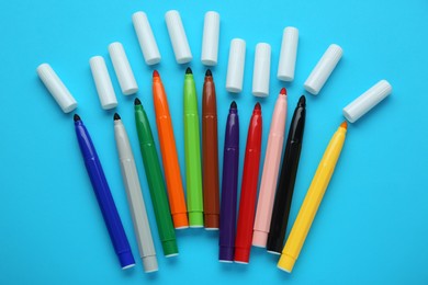 Photo of Many different colorful markers and caps on light blue background, flat lay