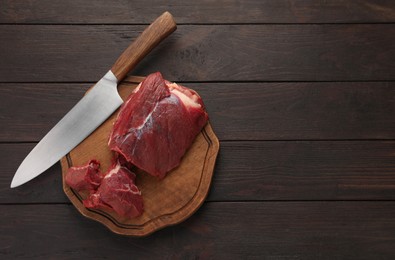 Photo of Pieces of raw beef meat and knife on wooden table, top view. Space for text