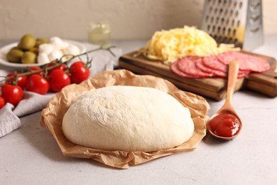 Photo of Pizza dough and products on gray textured table, closeup