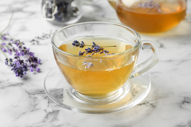 Photo of Fresh delicious tea with lavender and beautiful flowers on white marble table, closeup