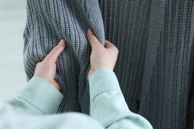 Woman touching clothes made of soft knitted fabric, closeup