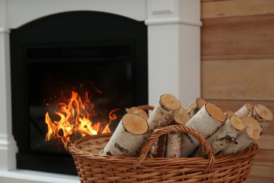Firewood in wicker basket near fireplace indoors