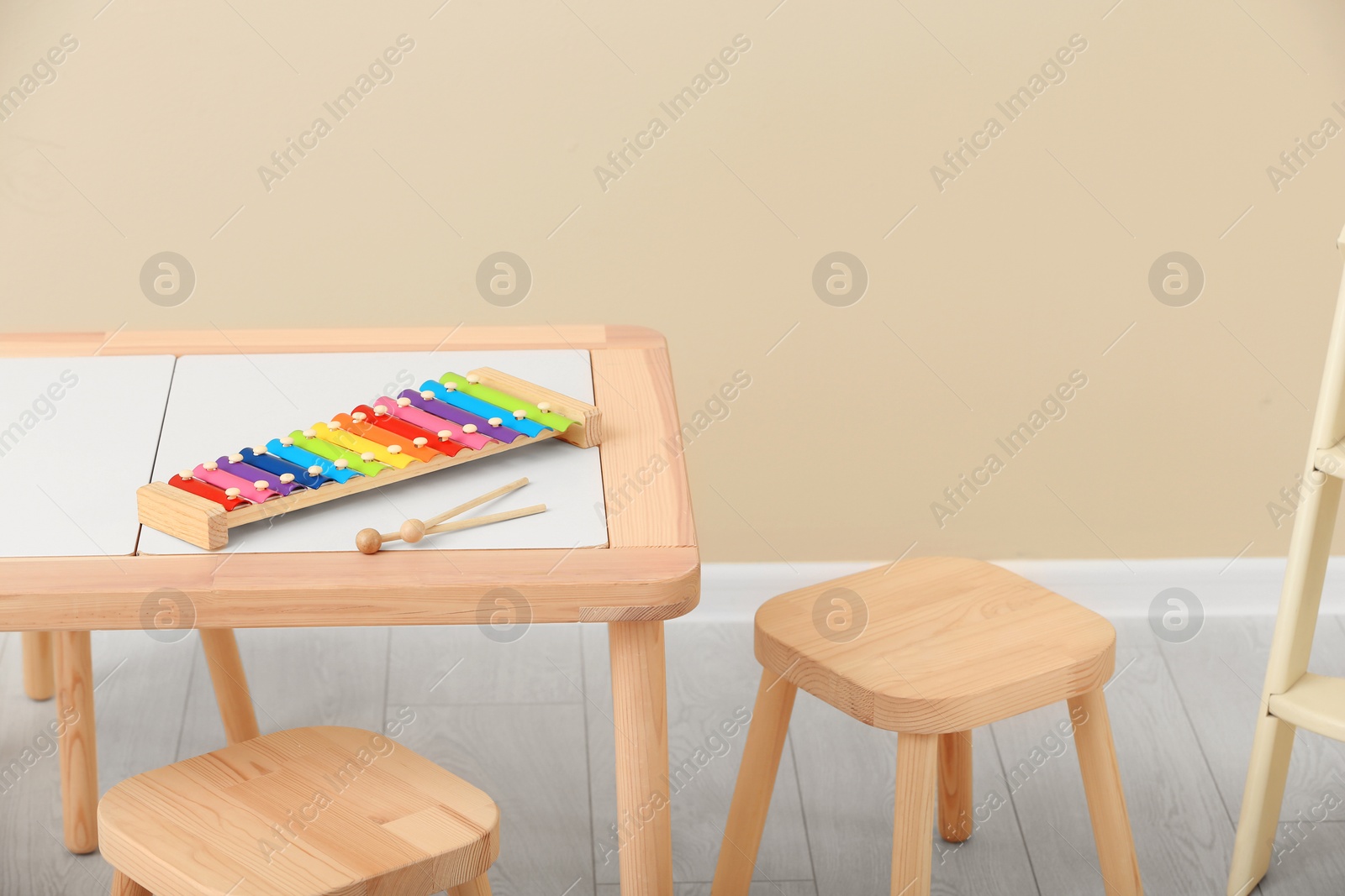 Photo of Stylish child's room interior with rainbow glockenspiel on wooden table