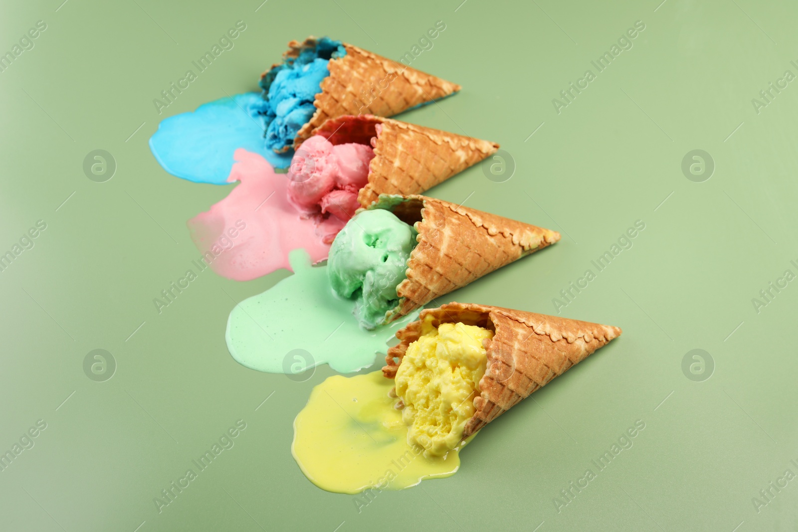 Photo of Melted ice cream in wafer cones on pale green background