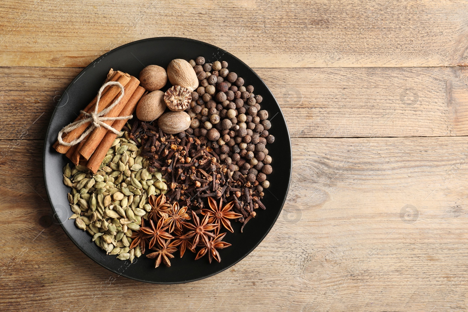 Photo of Different spices and nuts on wooden table, top view. Space for text