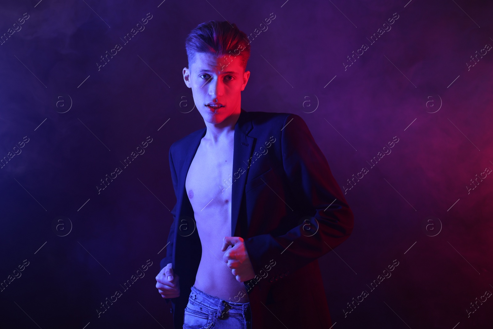 Photo of Sexy young man on dark background in neon lights