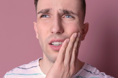 Photo of Young man with sensitive teeth on color background, closeup