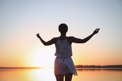 Woman near river on sunset. Healing concept