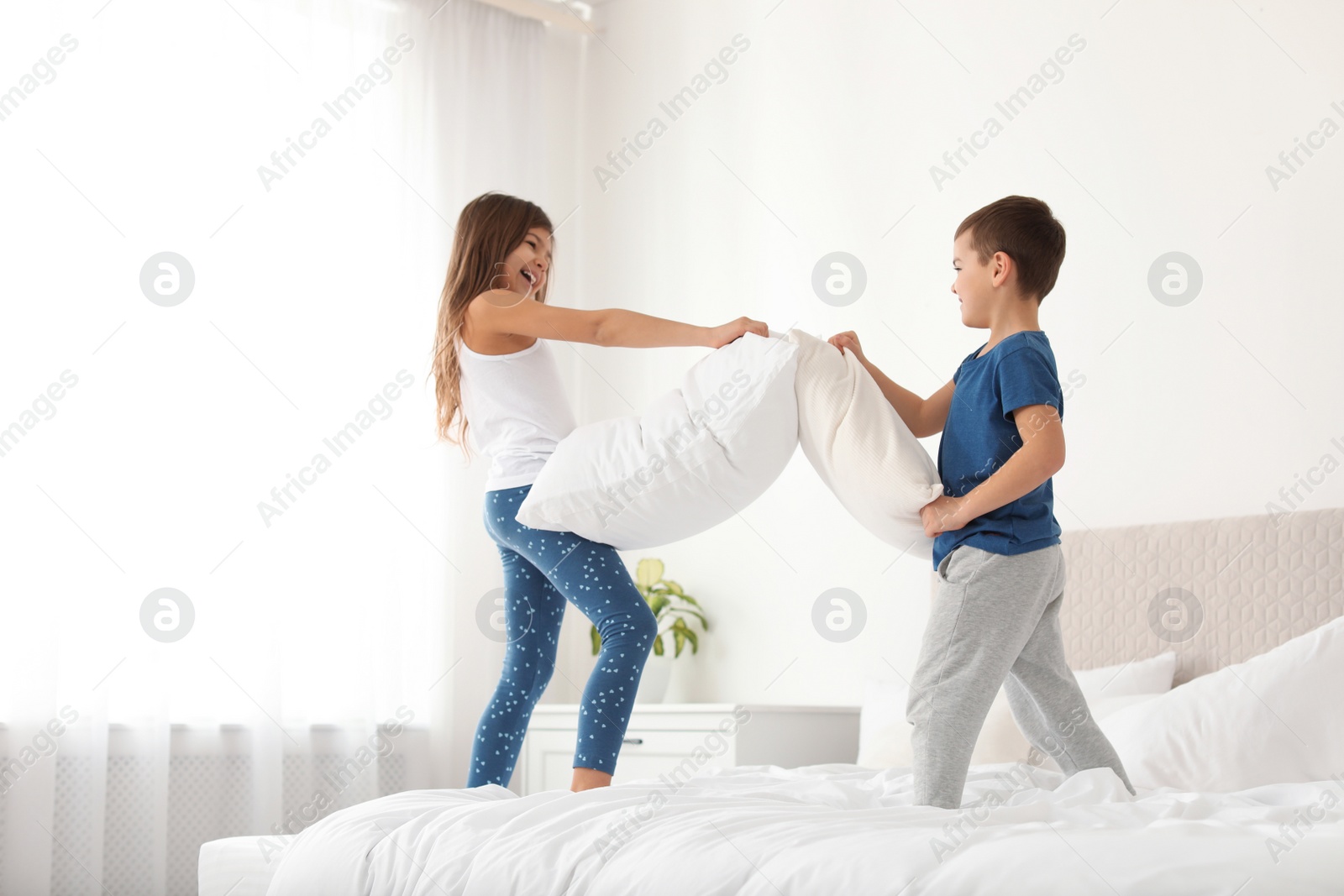 Photo of Happy children having pillow fight in bedroom