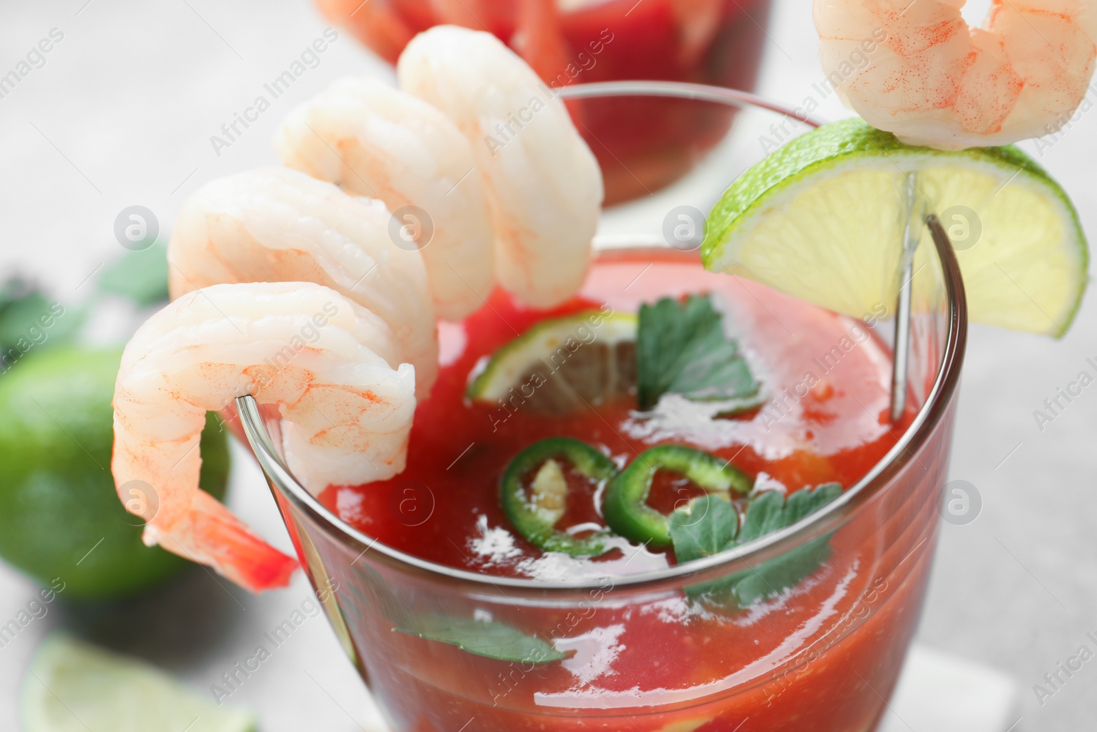 Photo of Tasty shrimp cocktail with sauce in glass and lime on light table, closeup