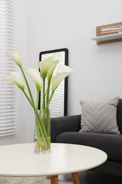 Photo of Beautiful calla lily flowers in glass vase on white table at home