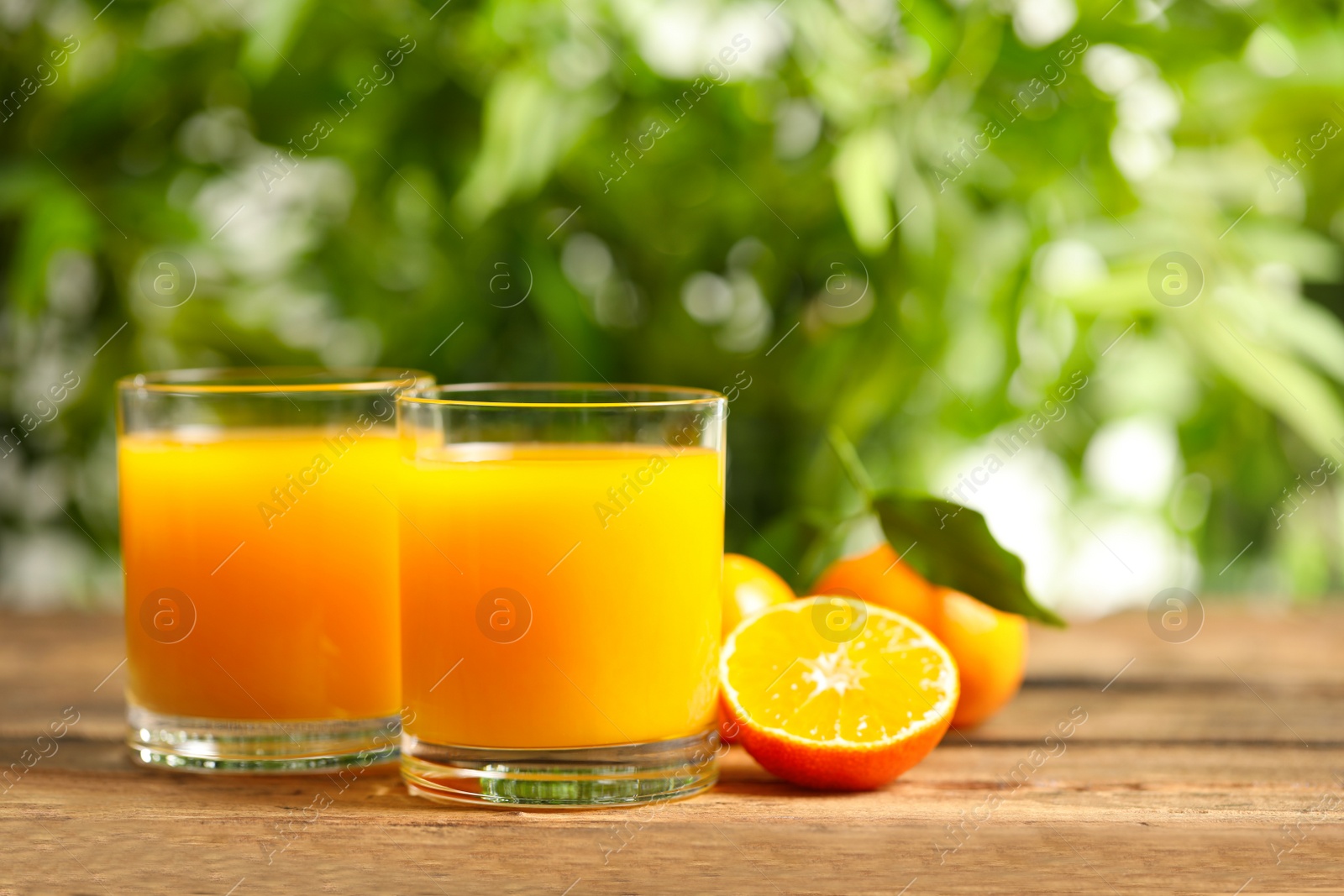 Photo of Glasses of fresh tangerine juice and fruits on wooden table