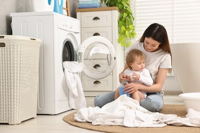 Mother with her daughter washing baby clothes in bathroom