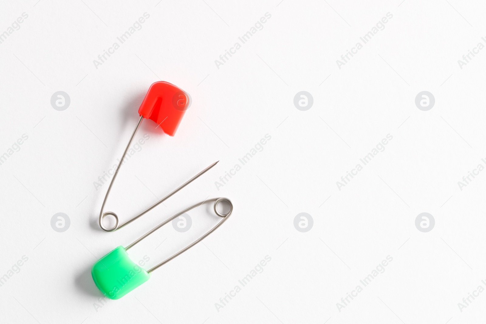 Photo of Colorful safety pins on white background, flat lay. Space for text