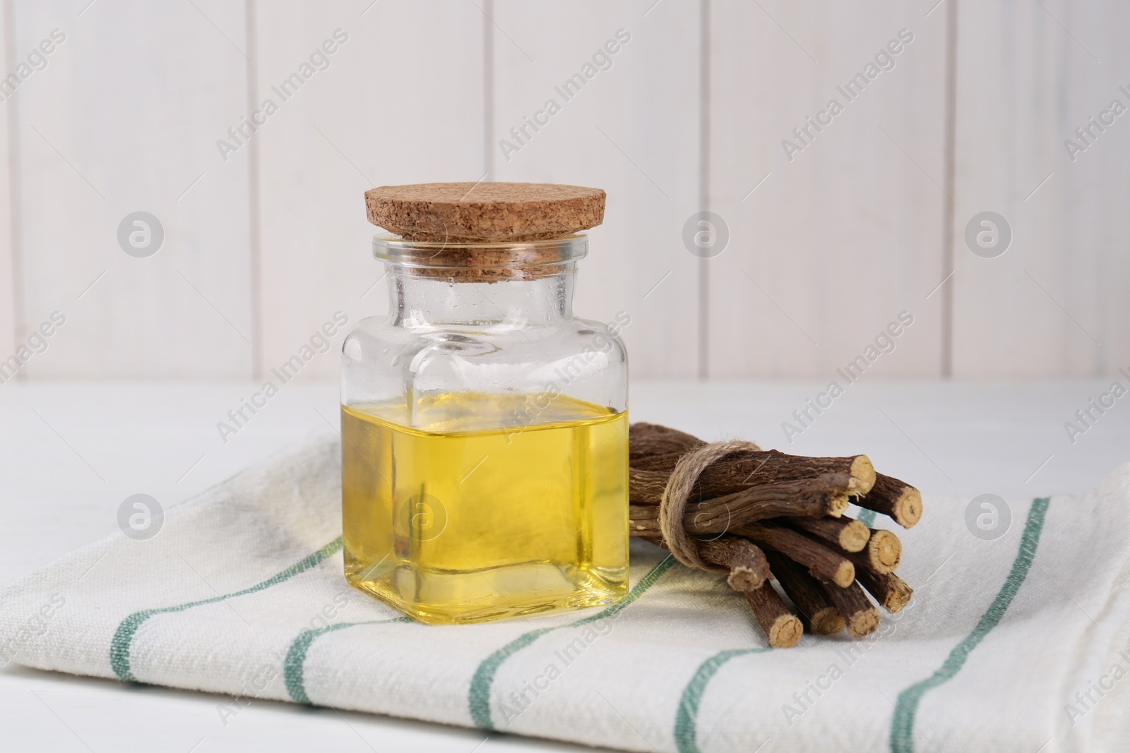 Photo of Dried sticks of licorice roots and essential oil on white table