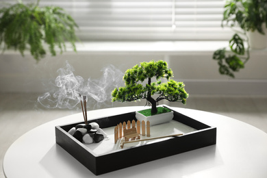 Photo of Beautiful miniature zen garden with incense sticks on table indoors