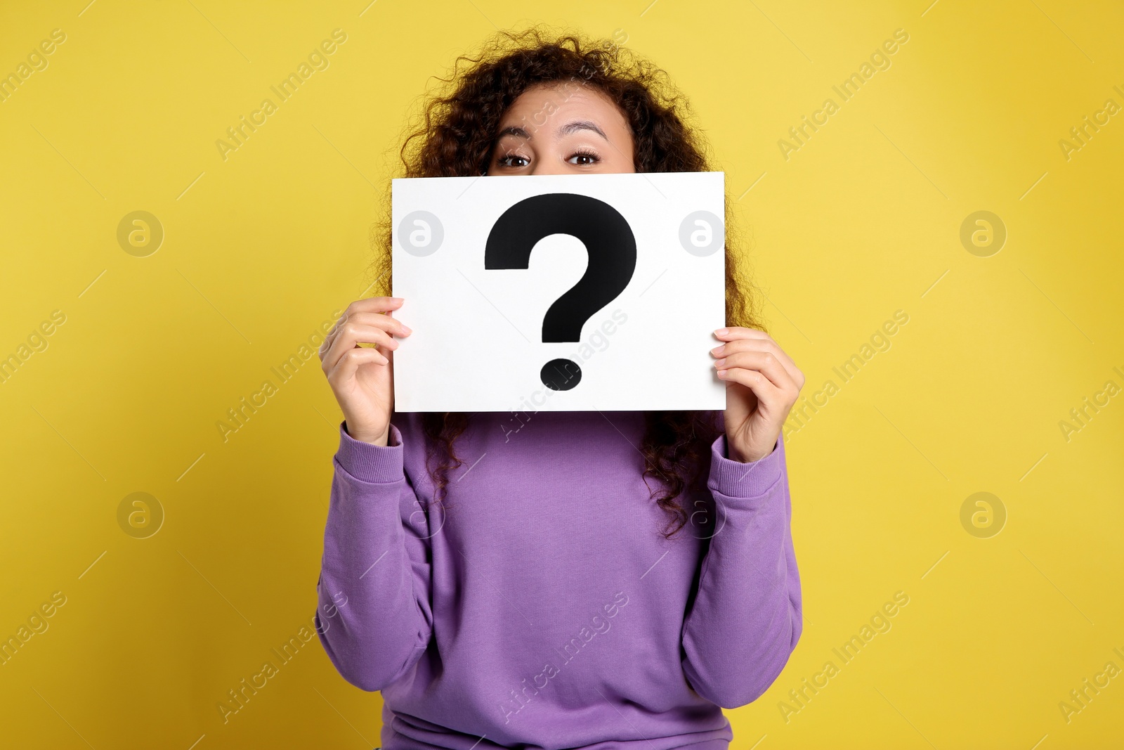 Photo of African-American woman with question mark sign on yellow background