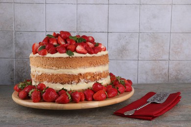 Photo of Tasty cake with fresh strawberries and mint served on gray table, space for text
