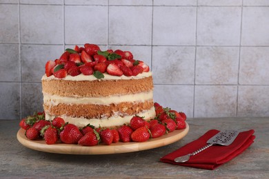 Tasty cake with fresh strawberries and mint served on gray table, space for text