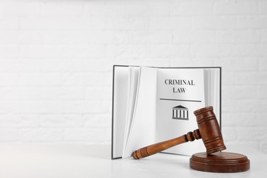 Photo of Book with words CRIMINAL LAW and gavel on table against white background. Space for text