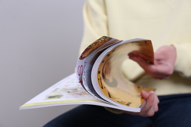 Woman reading magazine on light grey background, closeup