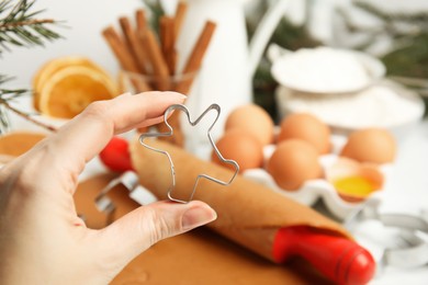 Woman holding cookie cutter at table, closeup. Christmas biscuits