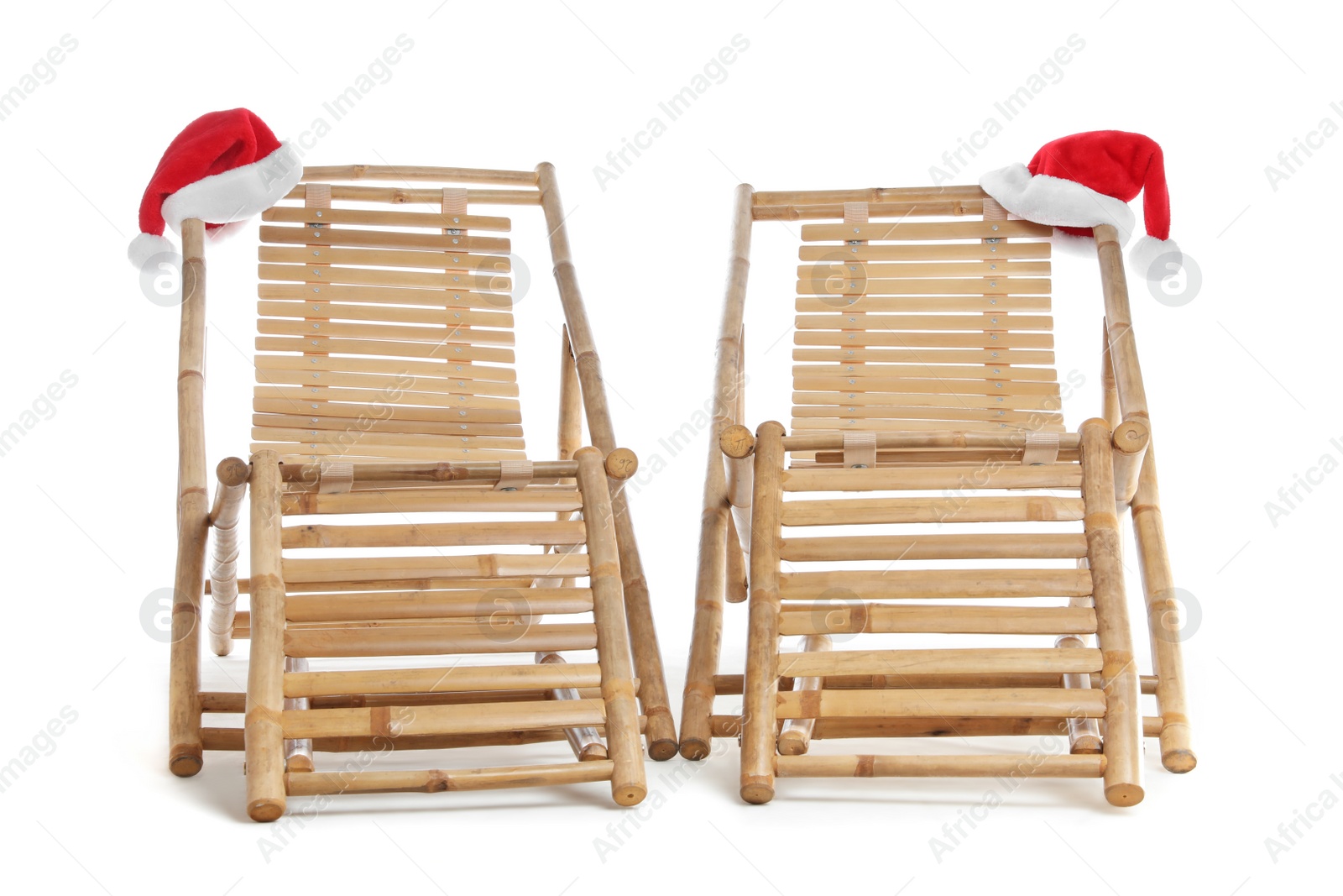 Photo of Wooden deck chairs and Santa Claus hats on white background. Christmas vacation