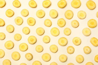 Slices of raw yellow carrot on beige background, flat lay